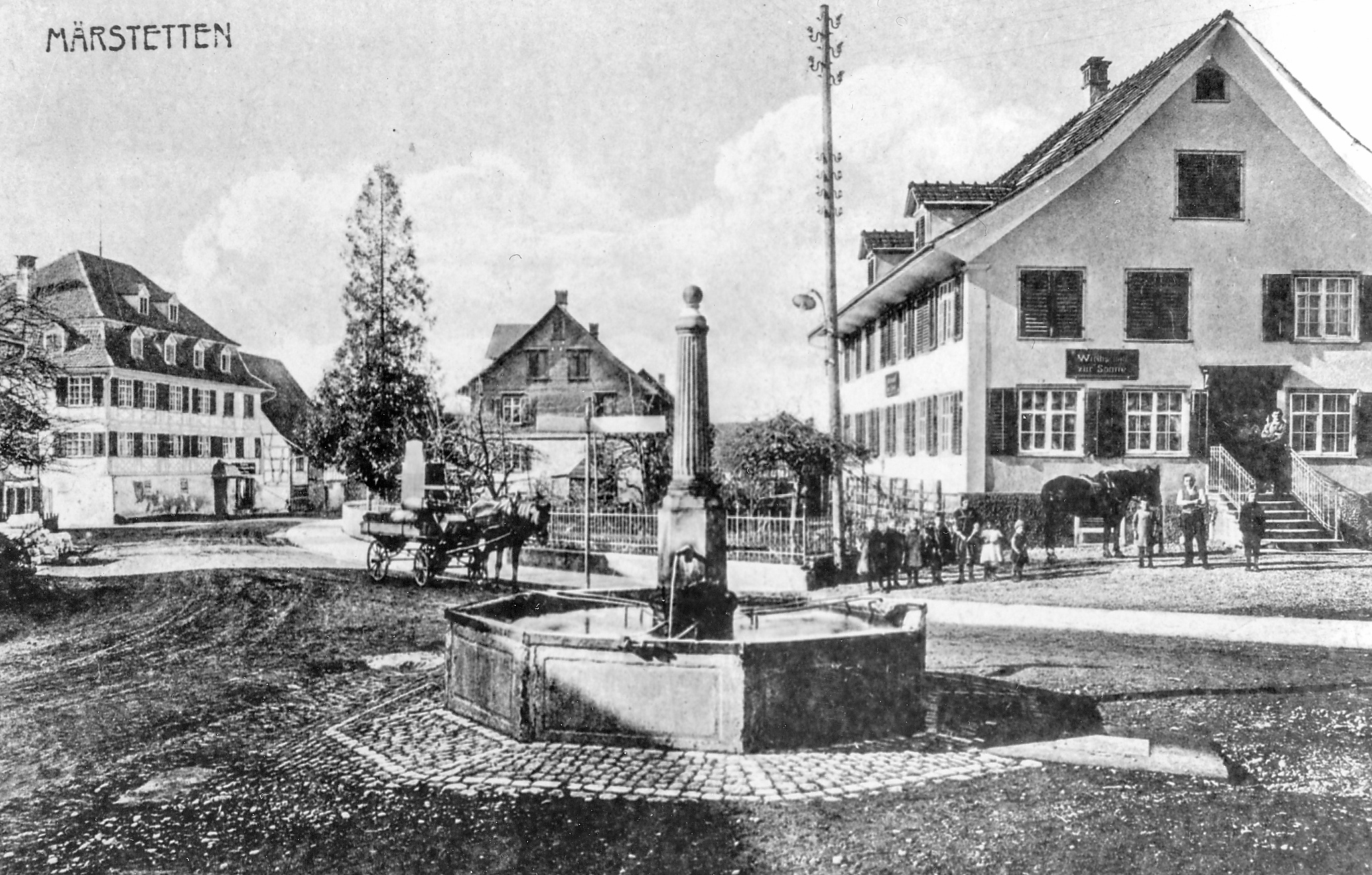 Dorfplatz mit Brunnen.